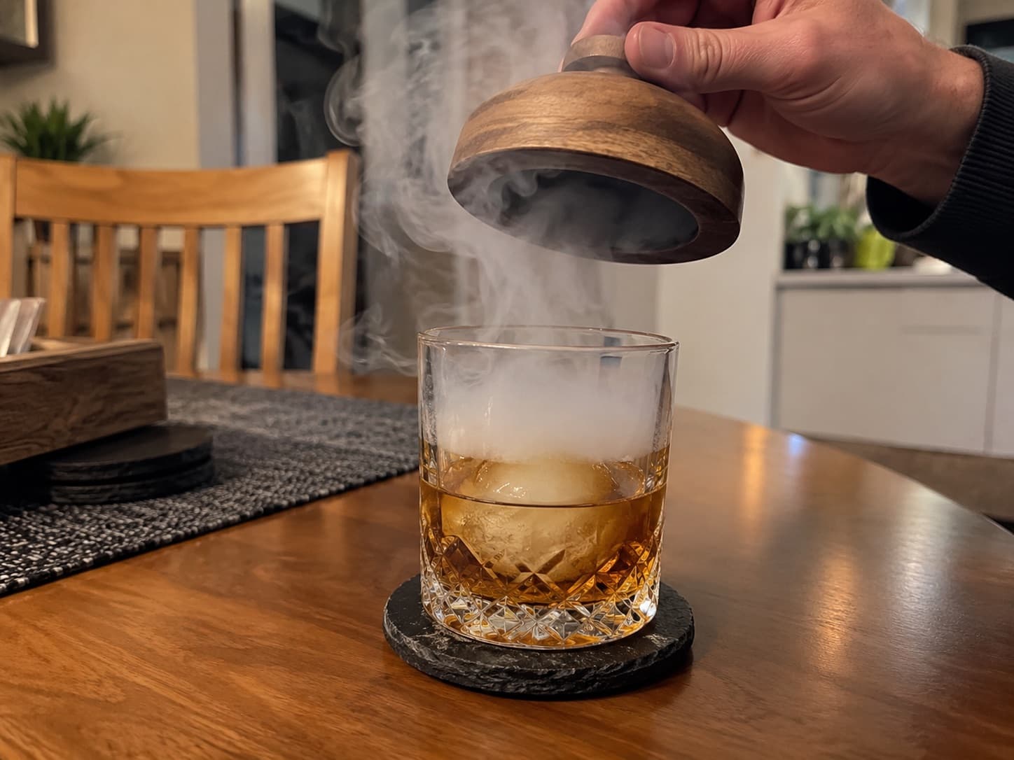 Lifting the smoker top off a tumbler of whisky, releasing the smoke